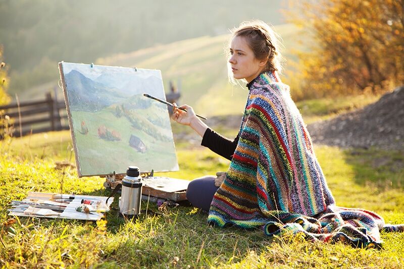 image of woman painting on a canvas in a field