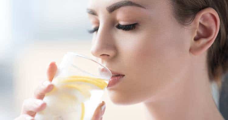 image of young woman drinkning water with lemon in it