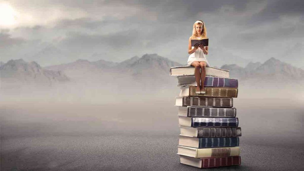 image of woman reading a book sitting on a pile of books